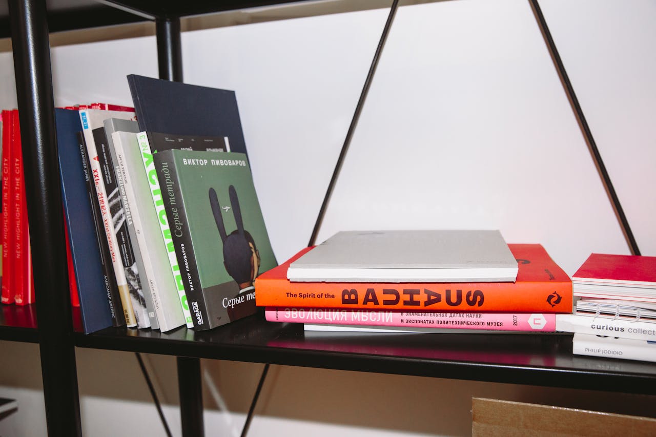 A variety of hardcover books neatly arranged on a modern bookshelf indoors.